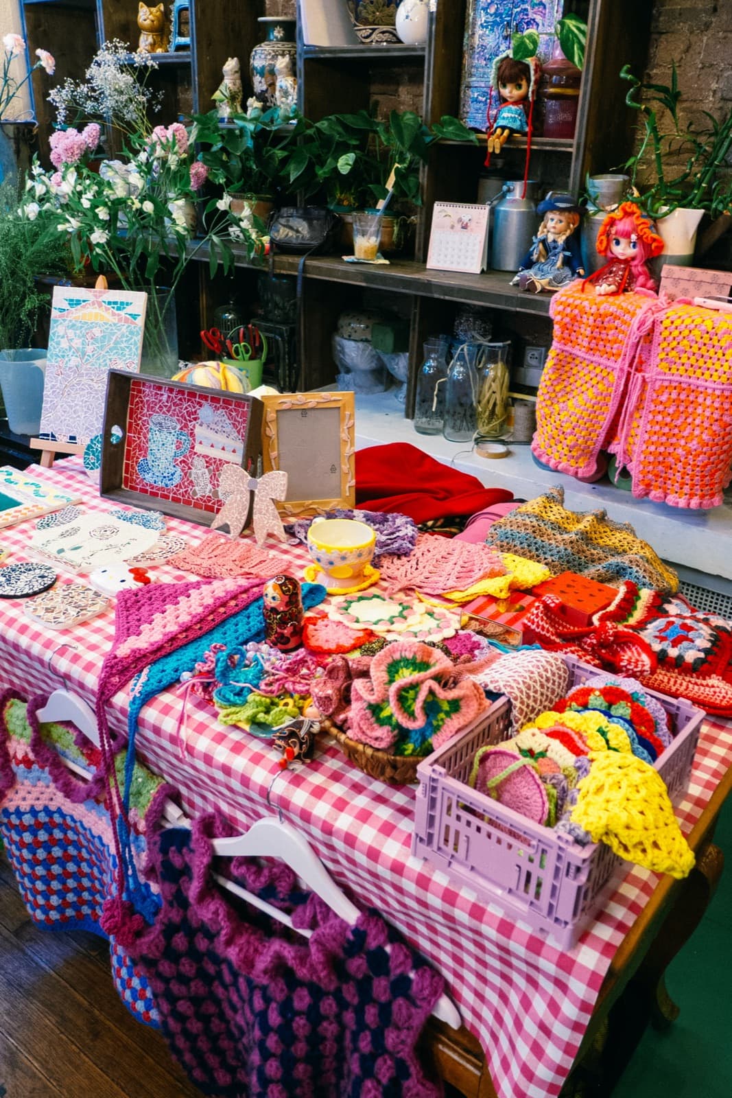 A gingham table covered in crochet bags, mosaics and ceramics